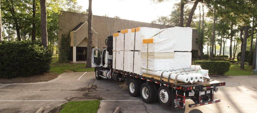 truck delivering commercial roofing supplies to a work site in Houston