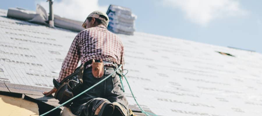 Questions to ask a roofer header showing man working on a new roof