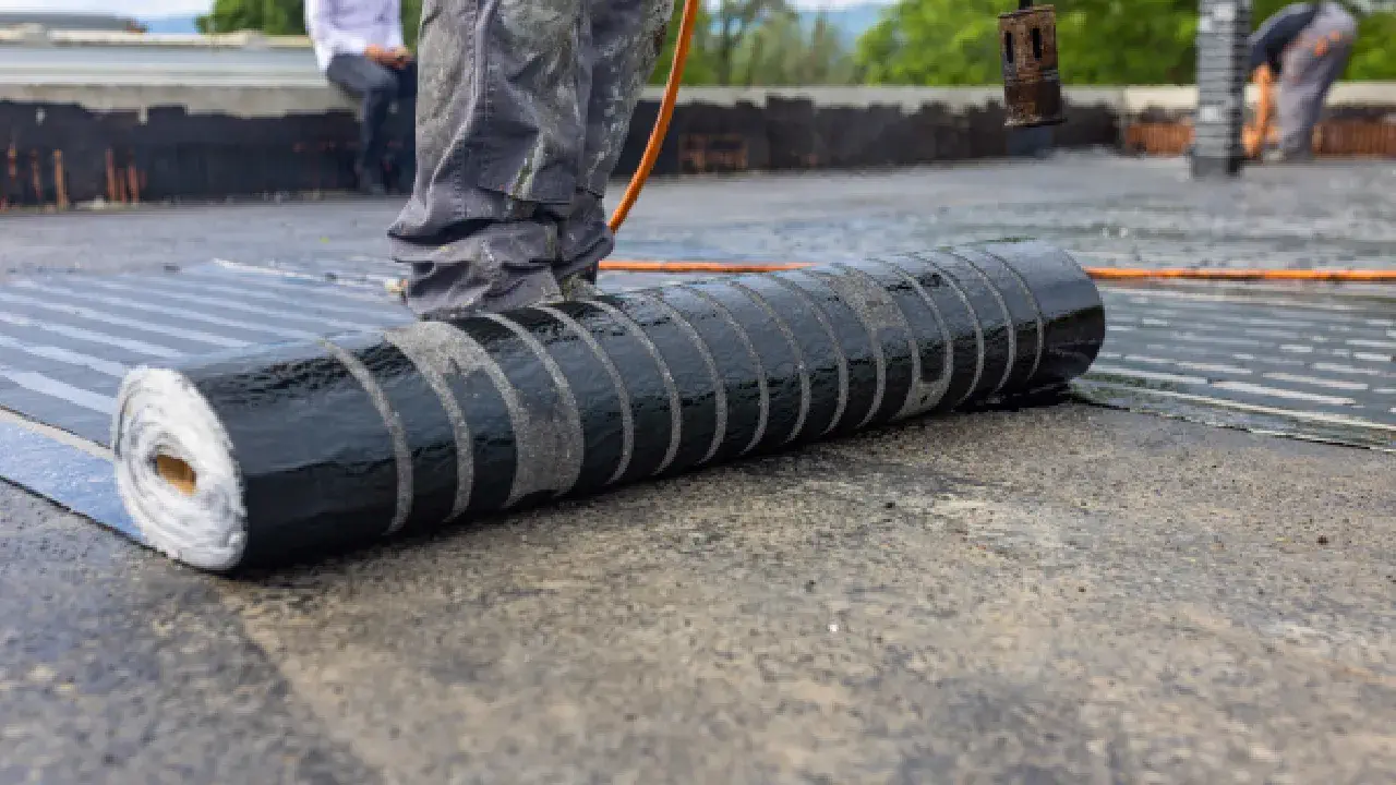 A professional roofer rolls out a black roof cover, showcasing techniques for flat roof repair